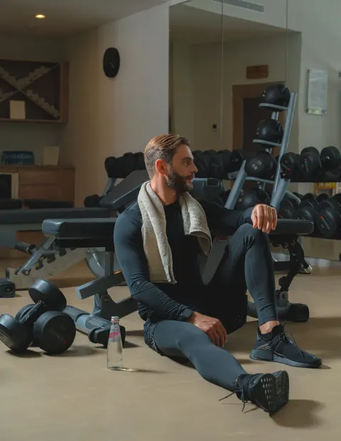 Guest resting beside dumbbells and benches in the fitness center at Eden Roc Cap Cana.
