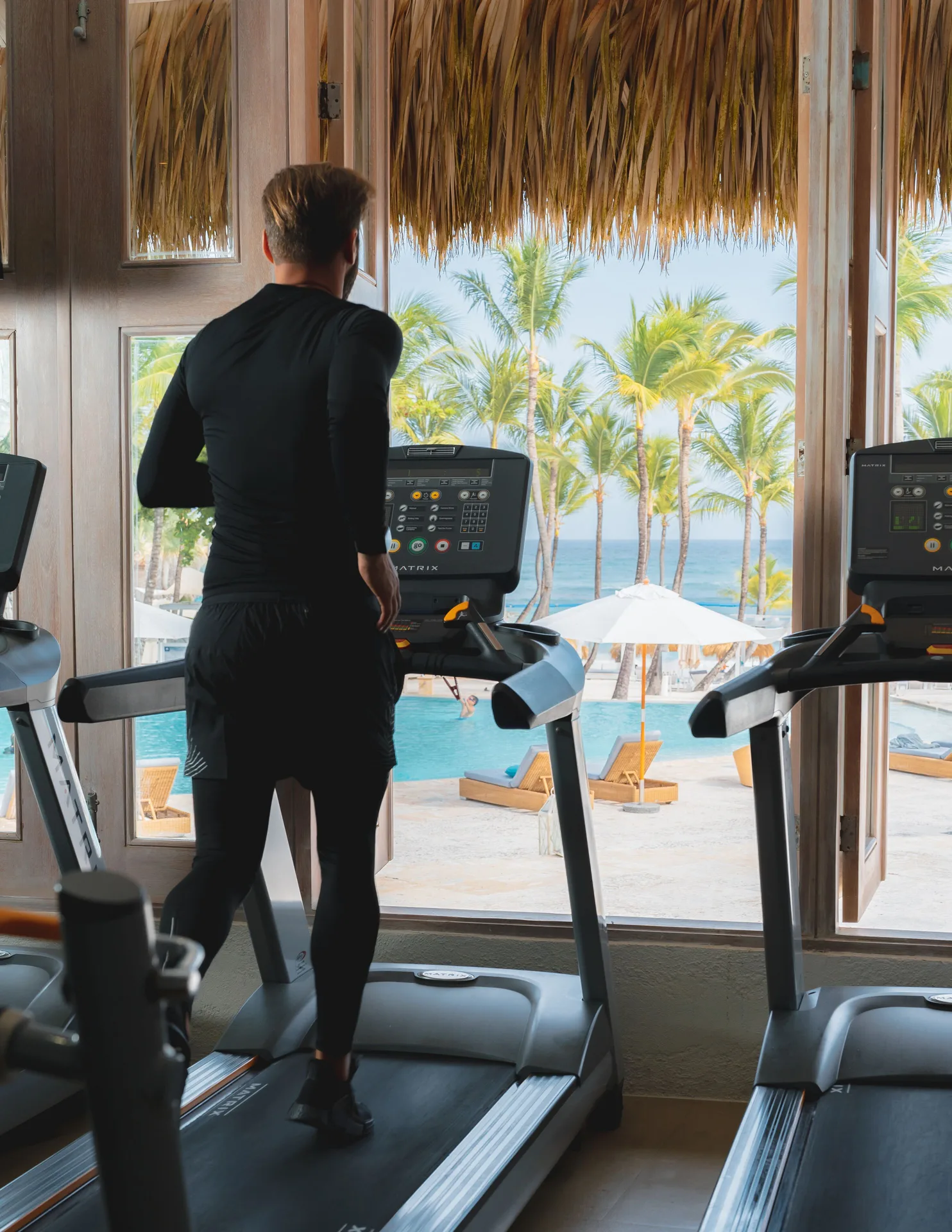 Guest running on a treadmill with pool and ocean views at Eden Roc Cap Cana.