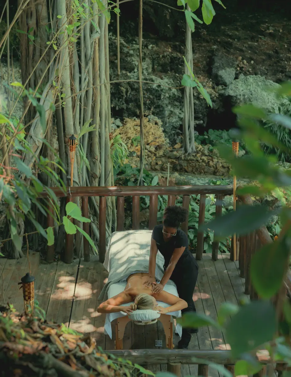 A guest receives an outdoor massage on a wooden deck at Eden Roc Cap Cana.