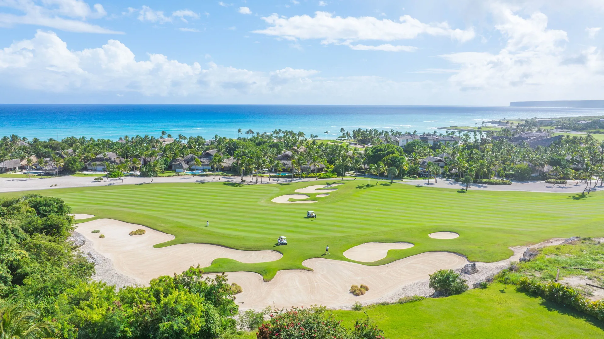 Aerial view of golf fairways, sand bunkers, palms, and ocean at Eden Roc Cap Cana.