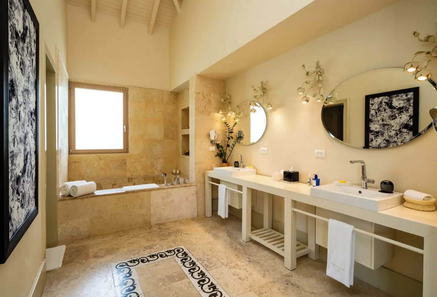 Guest bathroom with twin sinks, oval mirrors, and a bathtub at Eden Roc Cap Cana.