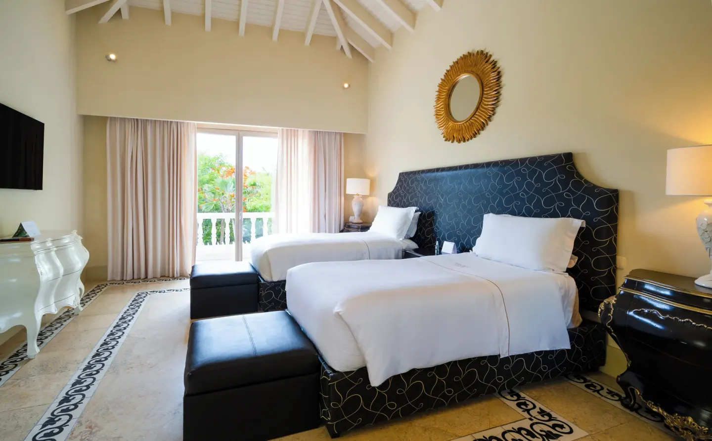 Guest room with two beds, vaulted ceiling, and balcony doors at Eden Roc Cap Cana.