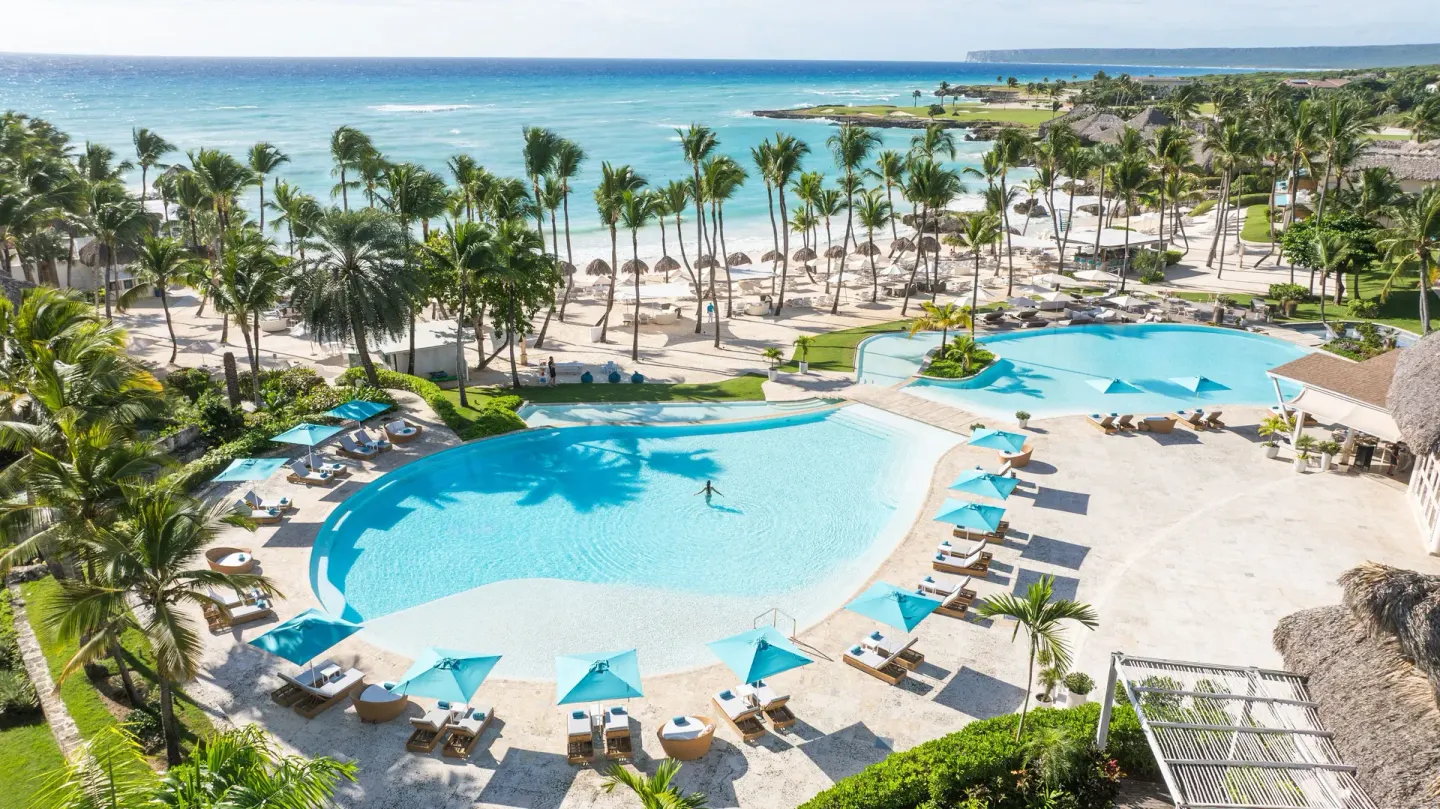 Resort pool with beach, palms, and turquoise sea beyond at Eden Roc Cap Cana.