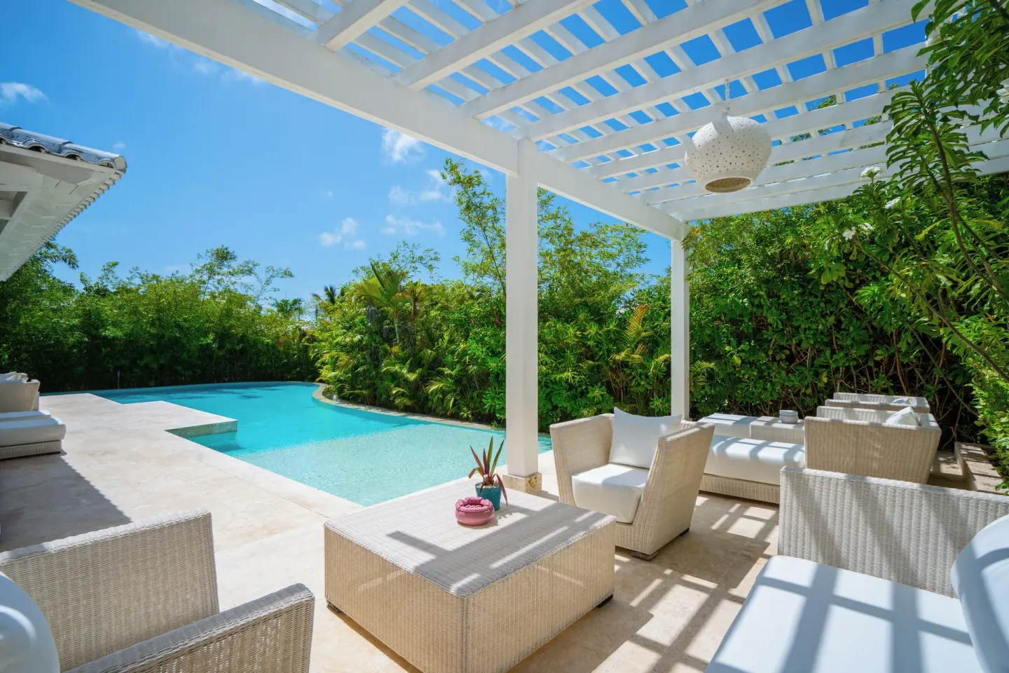 Shaded patio with white wicker seating beside a private pool at Eden Roc Cap Cana.