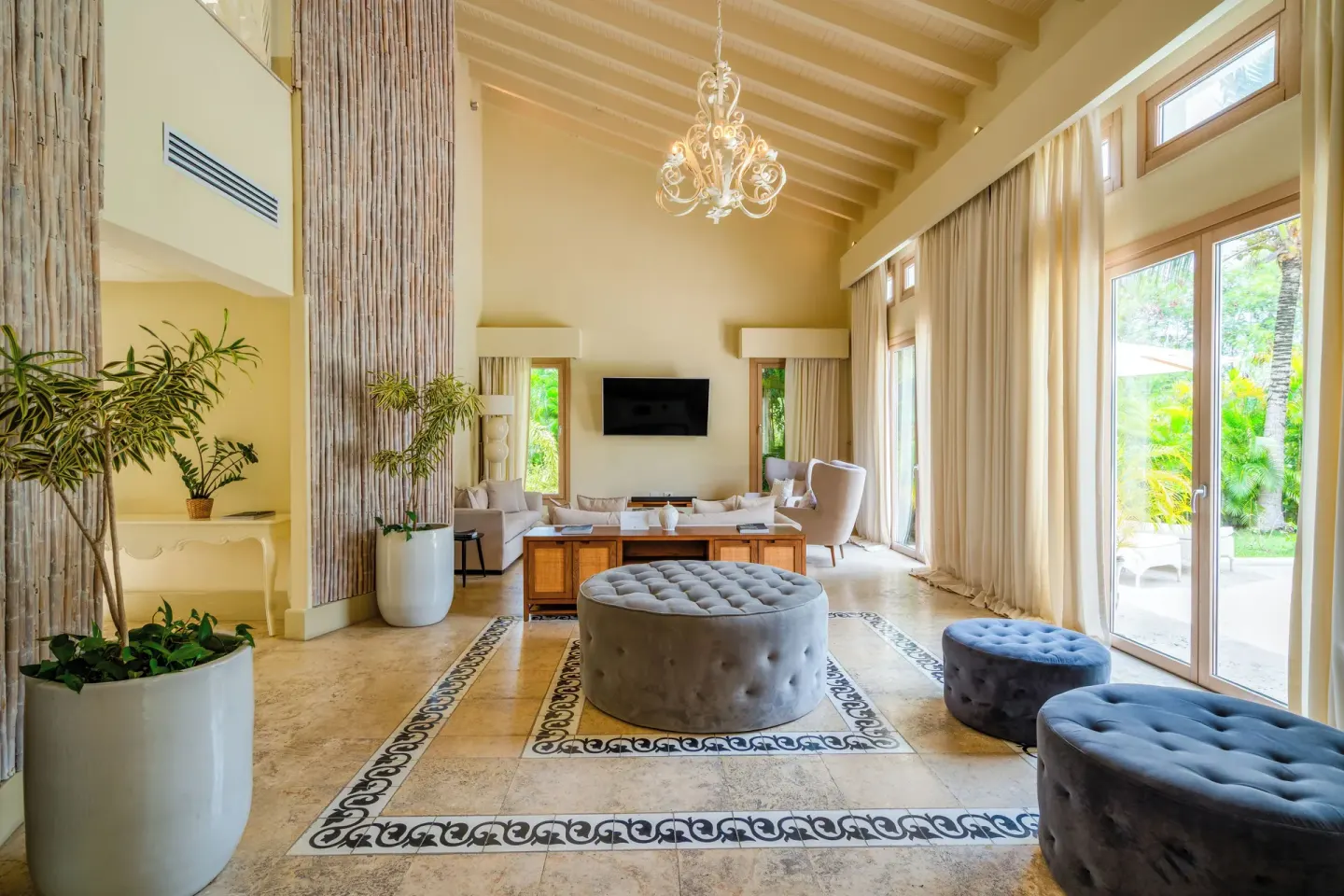 Spacious living room with chandelier, seating, tall windows, and garden views at Eden Roc Cap Cana.