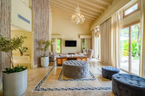 Spacious living room with chandelier, seating, tall windows, and garden views at Eden Roc Cap Cana.