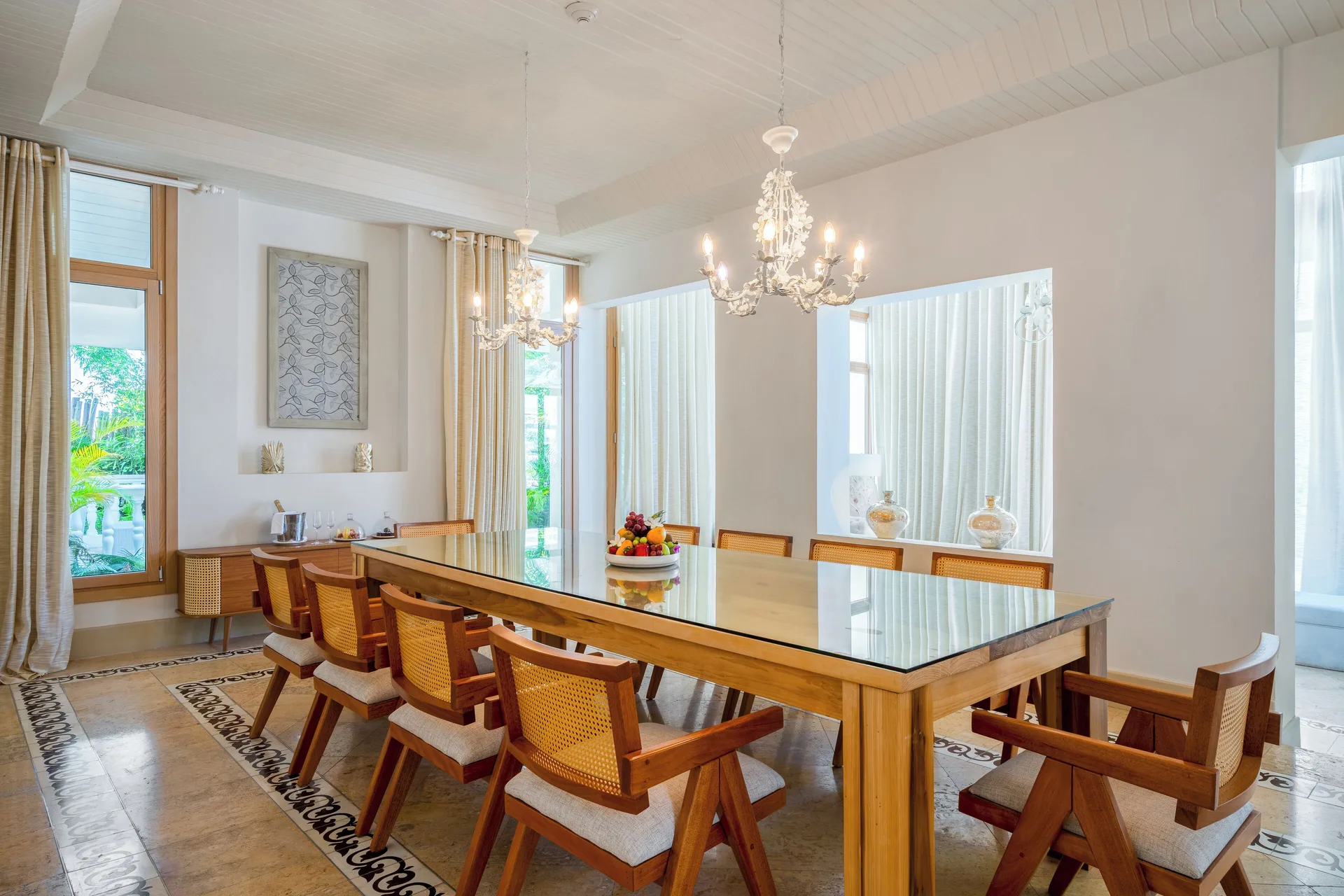 Dining room with a long table, cane chairs, and chandeliers at Eden Roc Cap Cana.