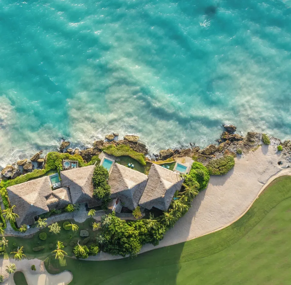 Top-down aerial view of oceanfront bungalows beside turquoise water at Eden Roc Cap Cana.