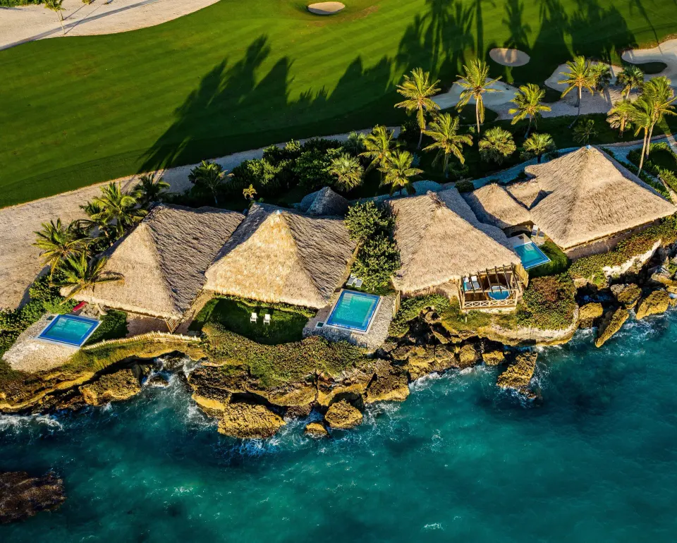 Aerial view of thatched oceanfront bungalows along the water at Eden Roc Cap Cana.