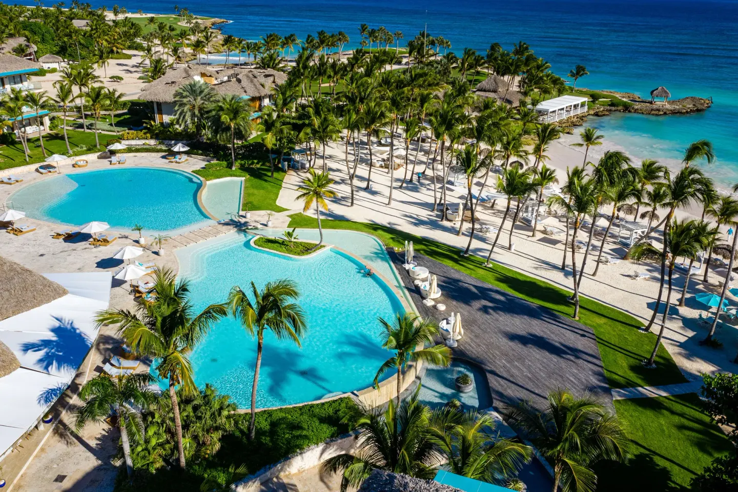 Aerial view of beachfront pools, palms and turquoise sea at Eden Roc Cap Cana.