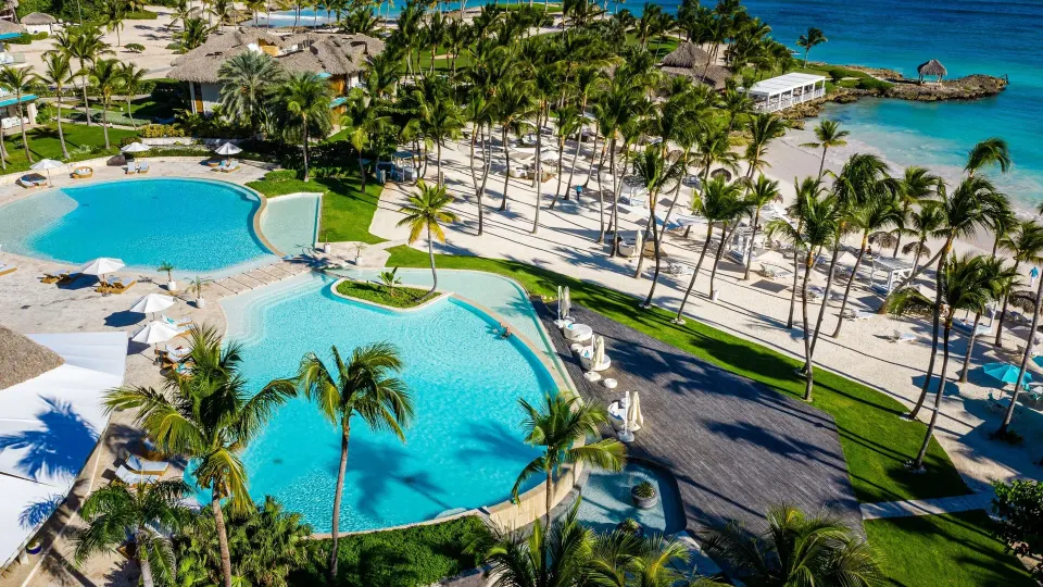 Aerial view of pools, beach and palms near beachfront suites at Eden Roc Cap Cana.