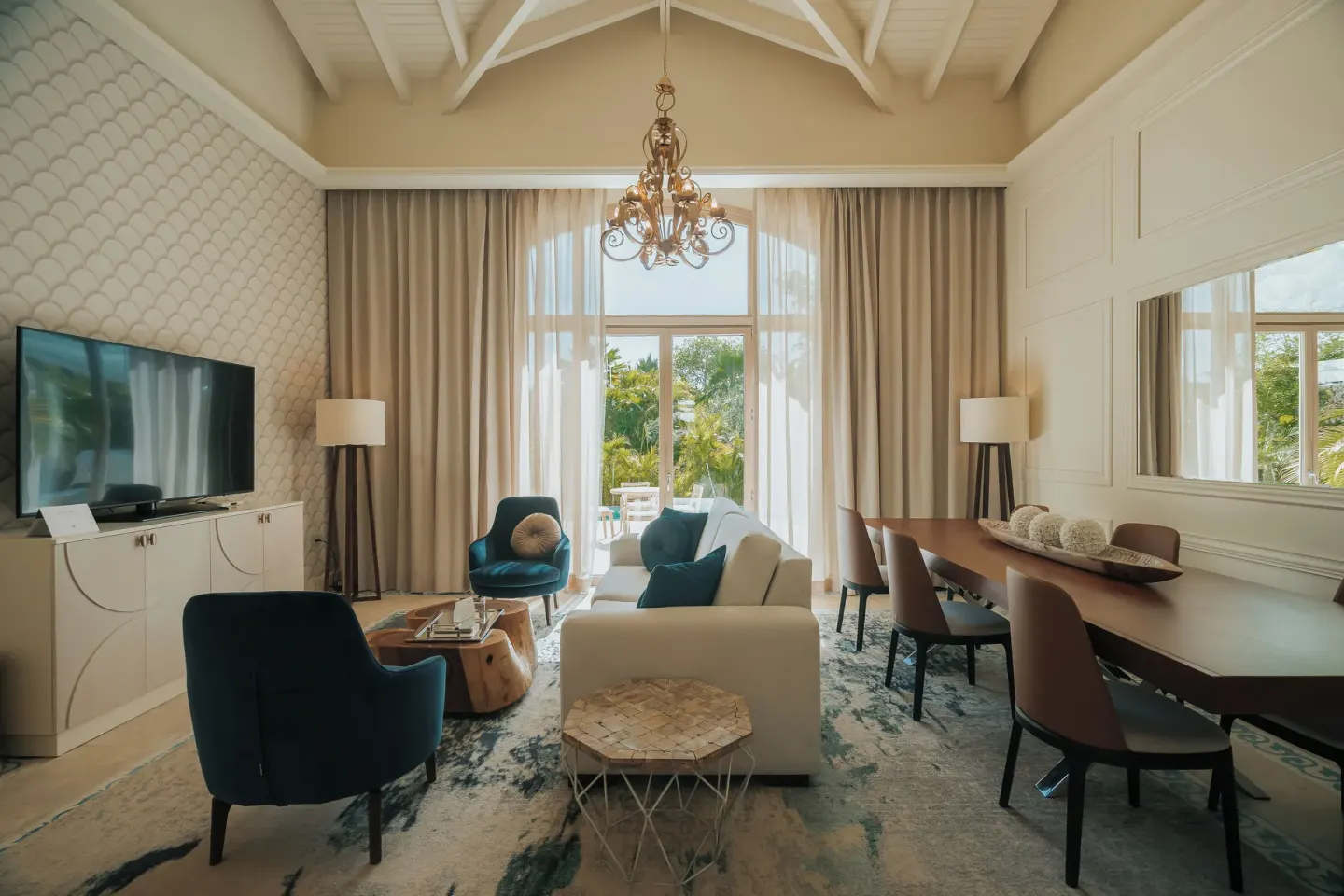 Living and dining area of a two-bedroom villa at Eden Roc Cap Cana with sofa, TV and long table.