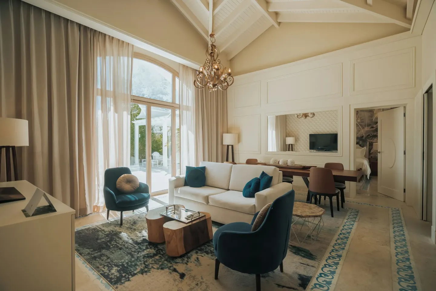 Two-bedroom villa living room at Eden Roc Cap Cana with sofa, blue chairs and terrace doors.