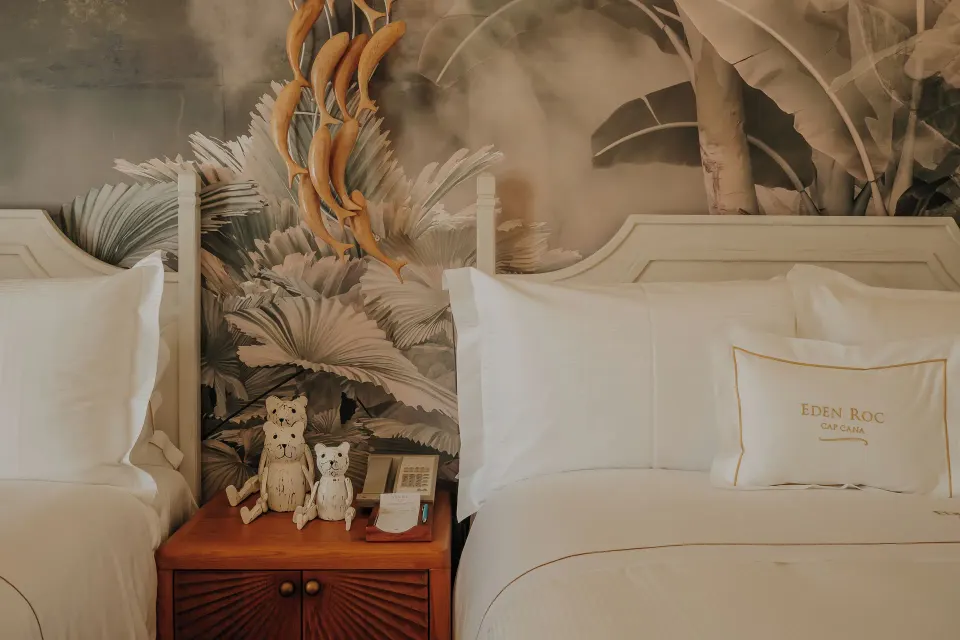 Two twin beds in a two-bedroom villa at Eden Roc Cap Cana with tropical wall art and bedside table.