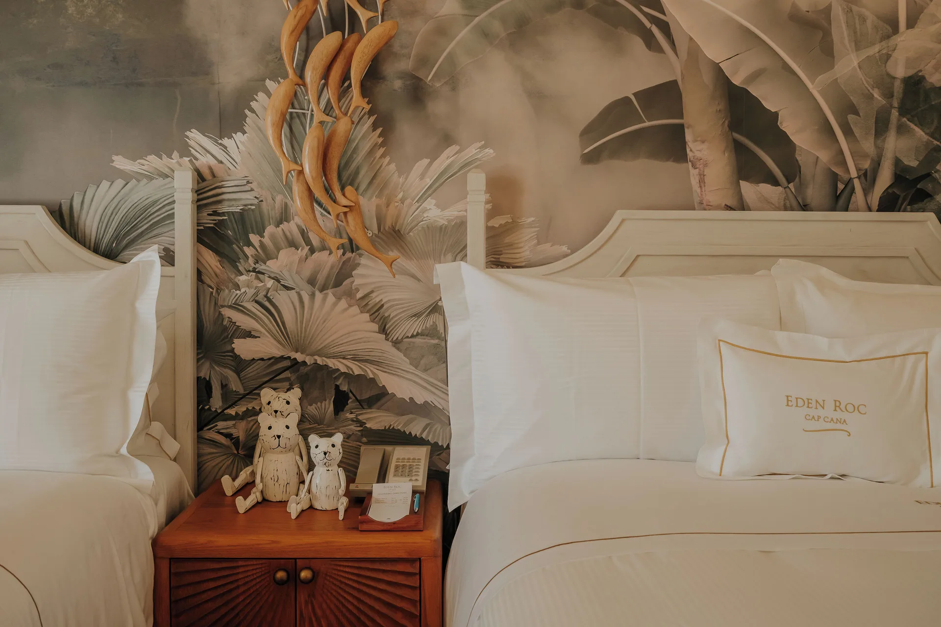 Two twin beds in a two-bedroom villa at Eden Roc Cap Cana with tropical wall art and bedside table.