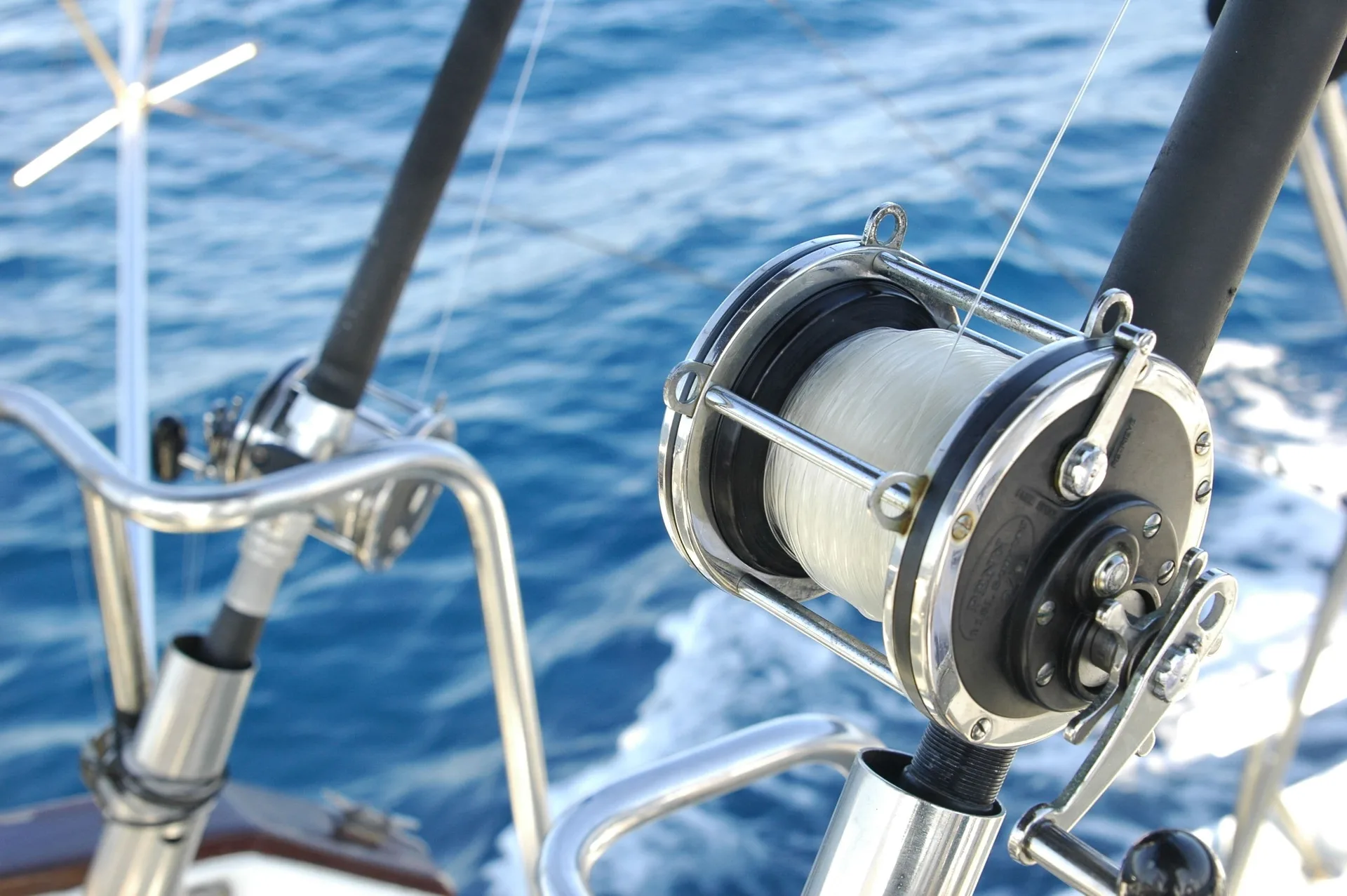 A fishing reel and rods are mounted on a boat over blue water at El Cid Castilla Beach Hotel.