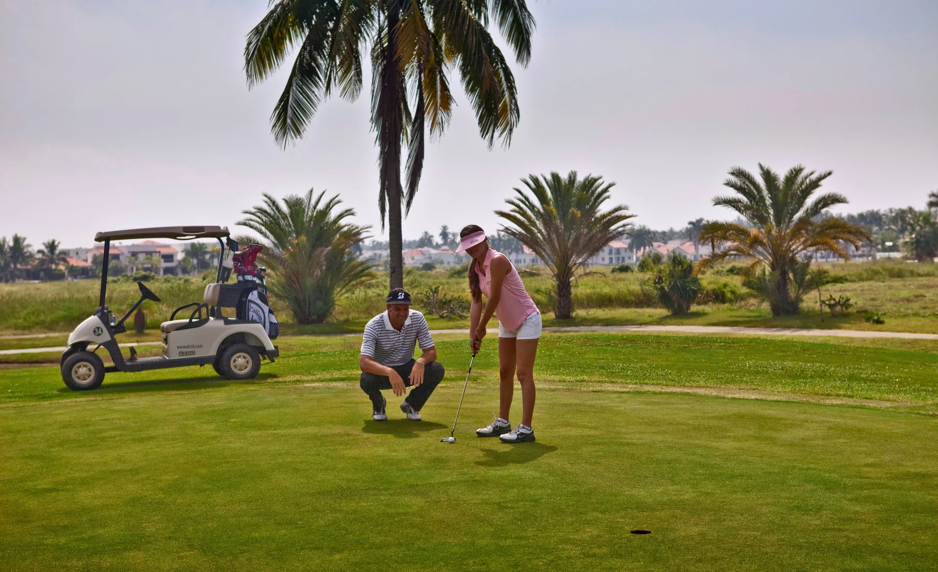 Guests practice putting on a palm-lined golf green near El Cid Castilla Beach Hotel.