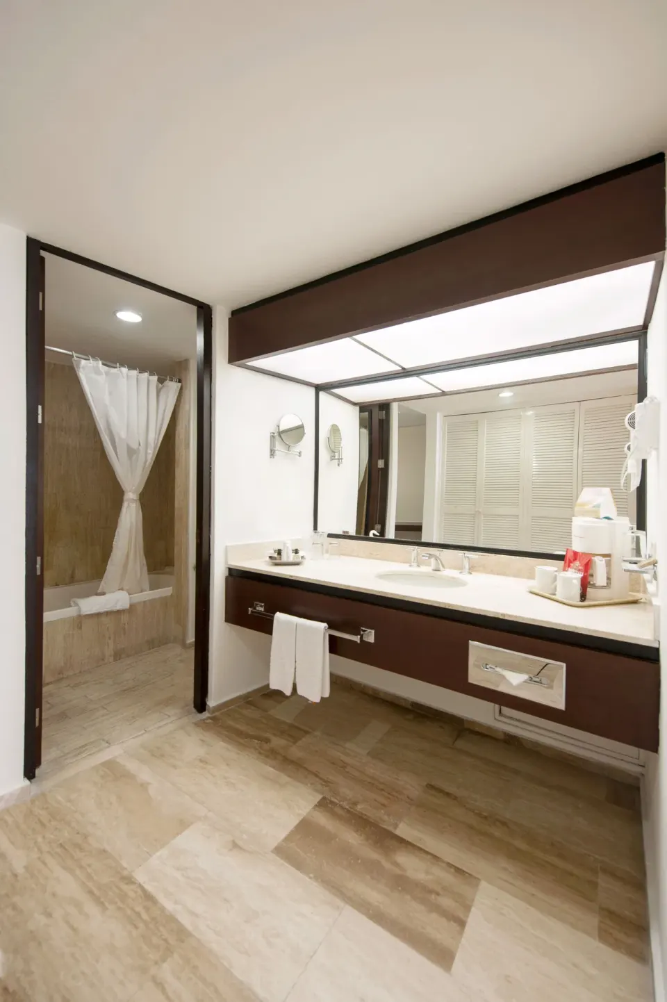 Guest bathroom with double vanity and curtained tub at El Cid Castilla Beach Hotel.