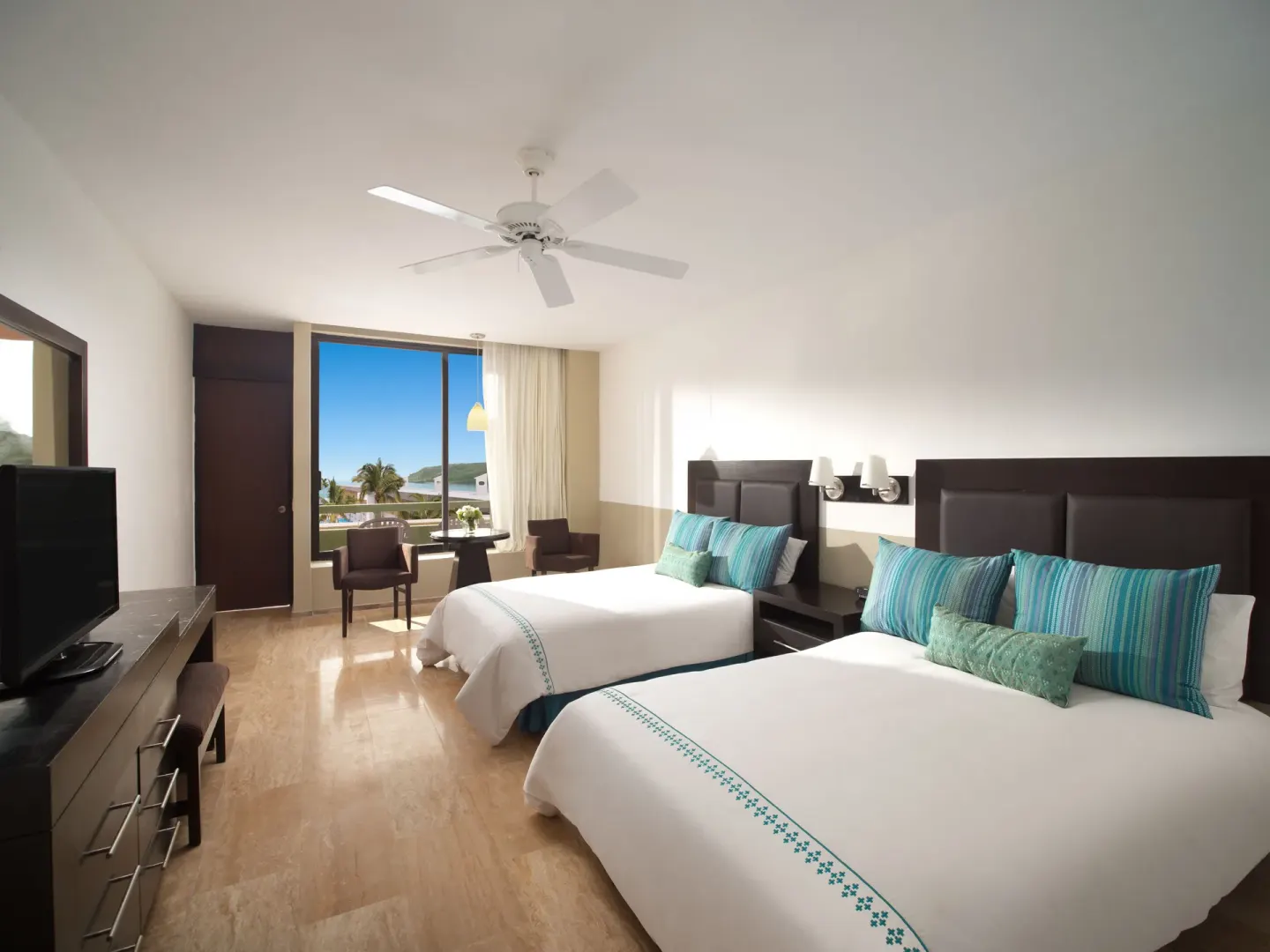 Two-bed guest room with coastal view at El Cid Castilla Beach Hotel.