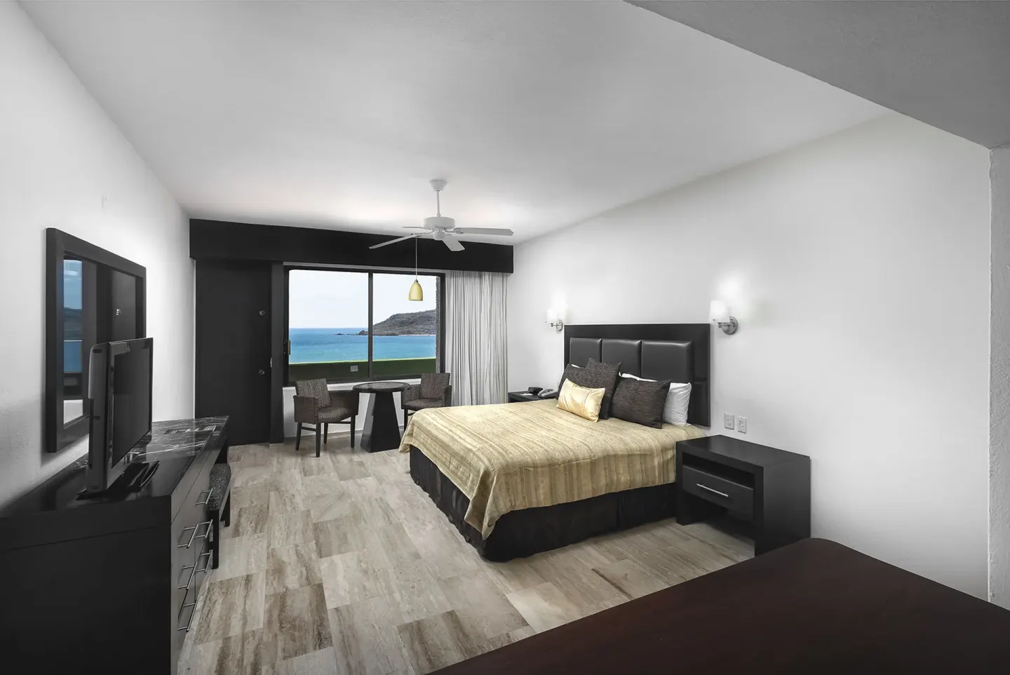 King bed guest room with ocean and hillside view at El Cid Castilla Beach Hotel.