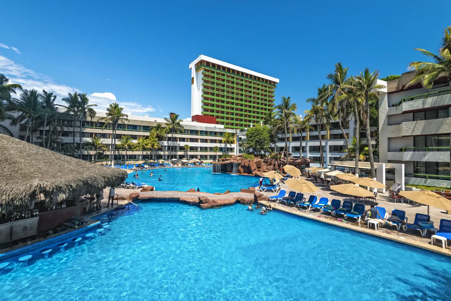 Resort pool with lounge chairs and palms at El Cid Castilla Beach Hotel.