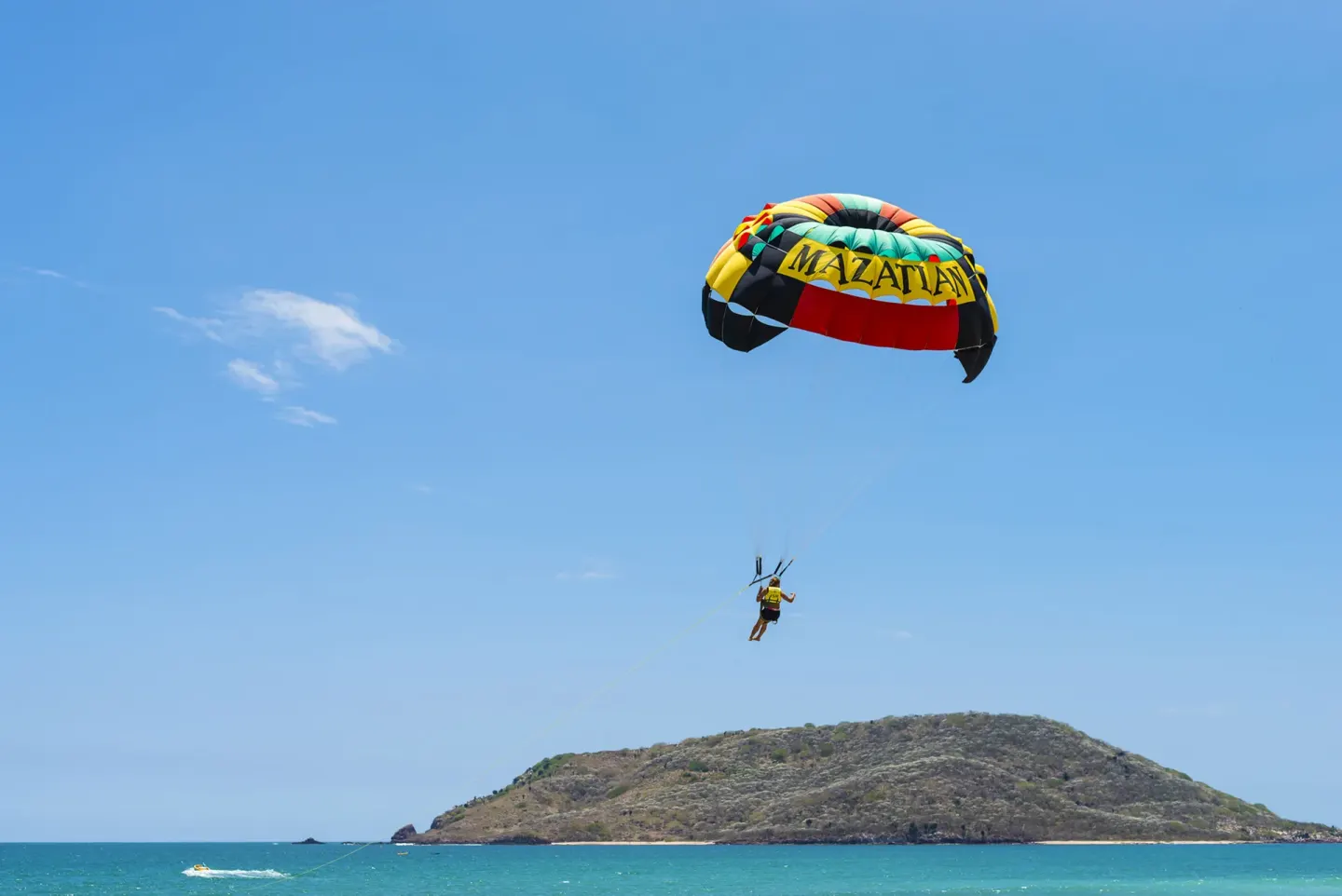 A parasailer glides over the water near El Cid Castilla Beach Hotel.