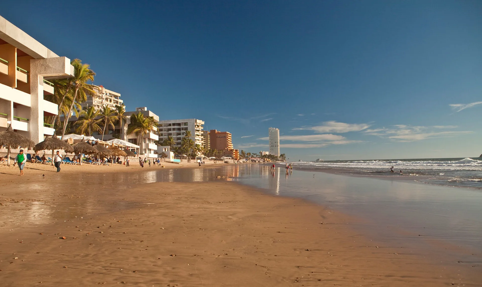 Wide sandy shoreline with resort buildings beside El Cid Castilla Beach Hotel.