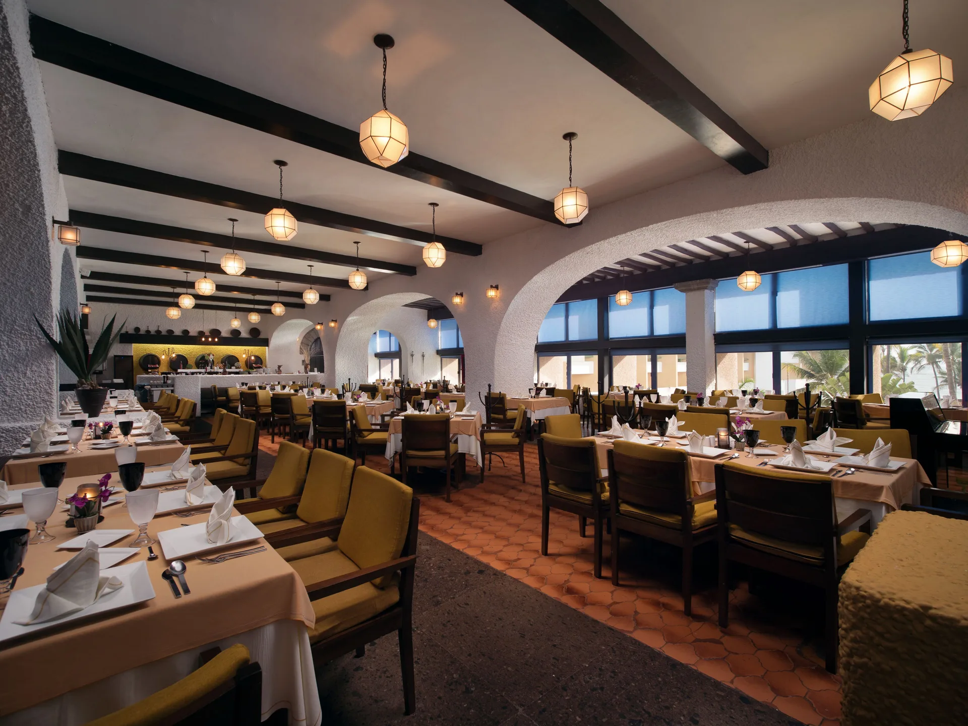 Arched dining room with set tables and pendant lights at El Cid Castilla Beach Hotel.