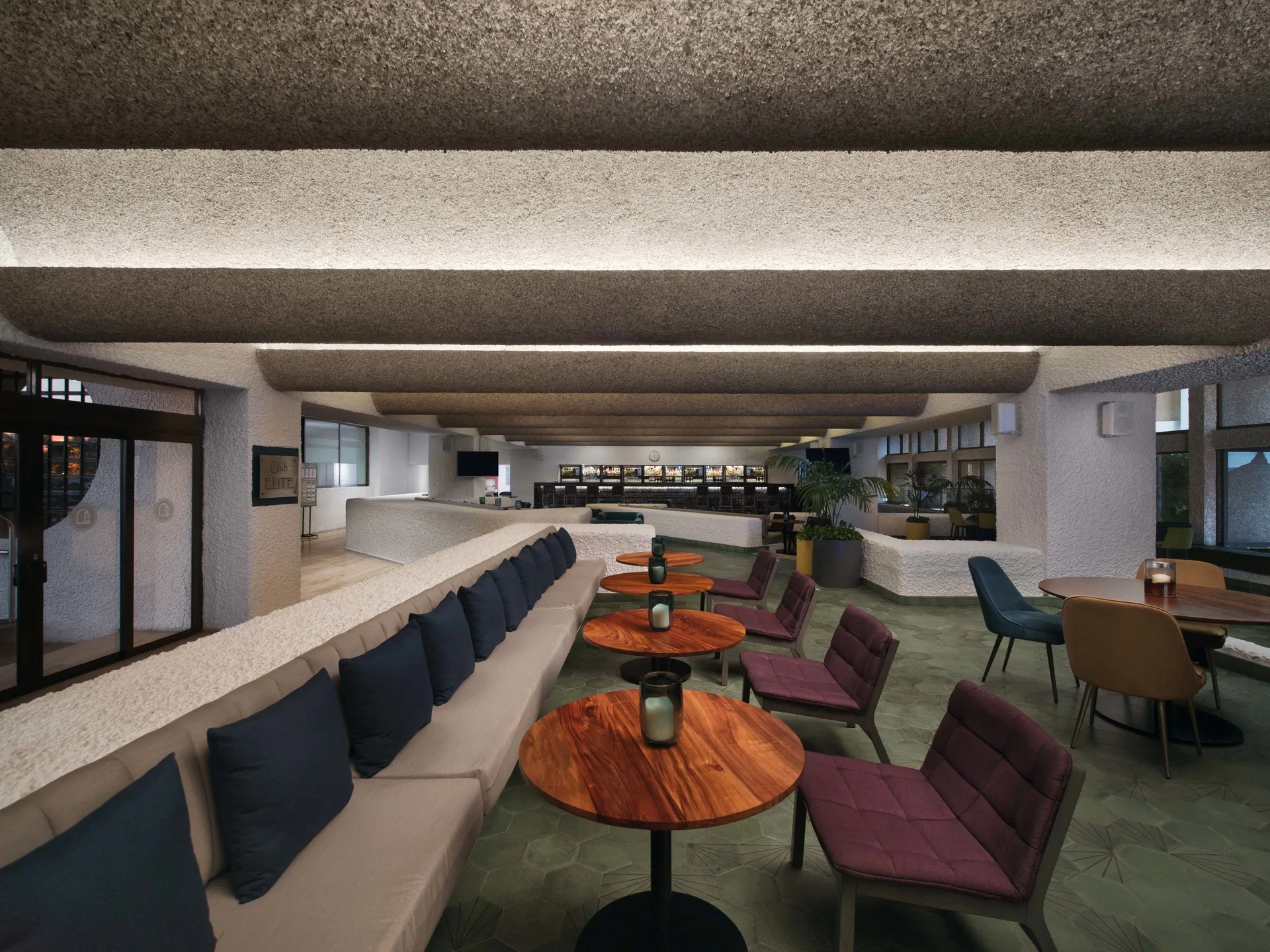 Lounge seating with round tables inside a lobby bar at El Cid Castilla Beach Hotel.