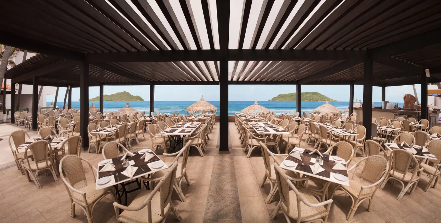 Oceanfront open-air dining terrace with set tables at El Cid Castilla Beach Hotel.