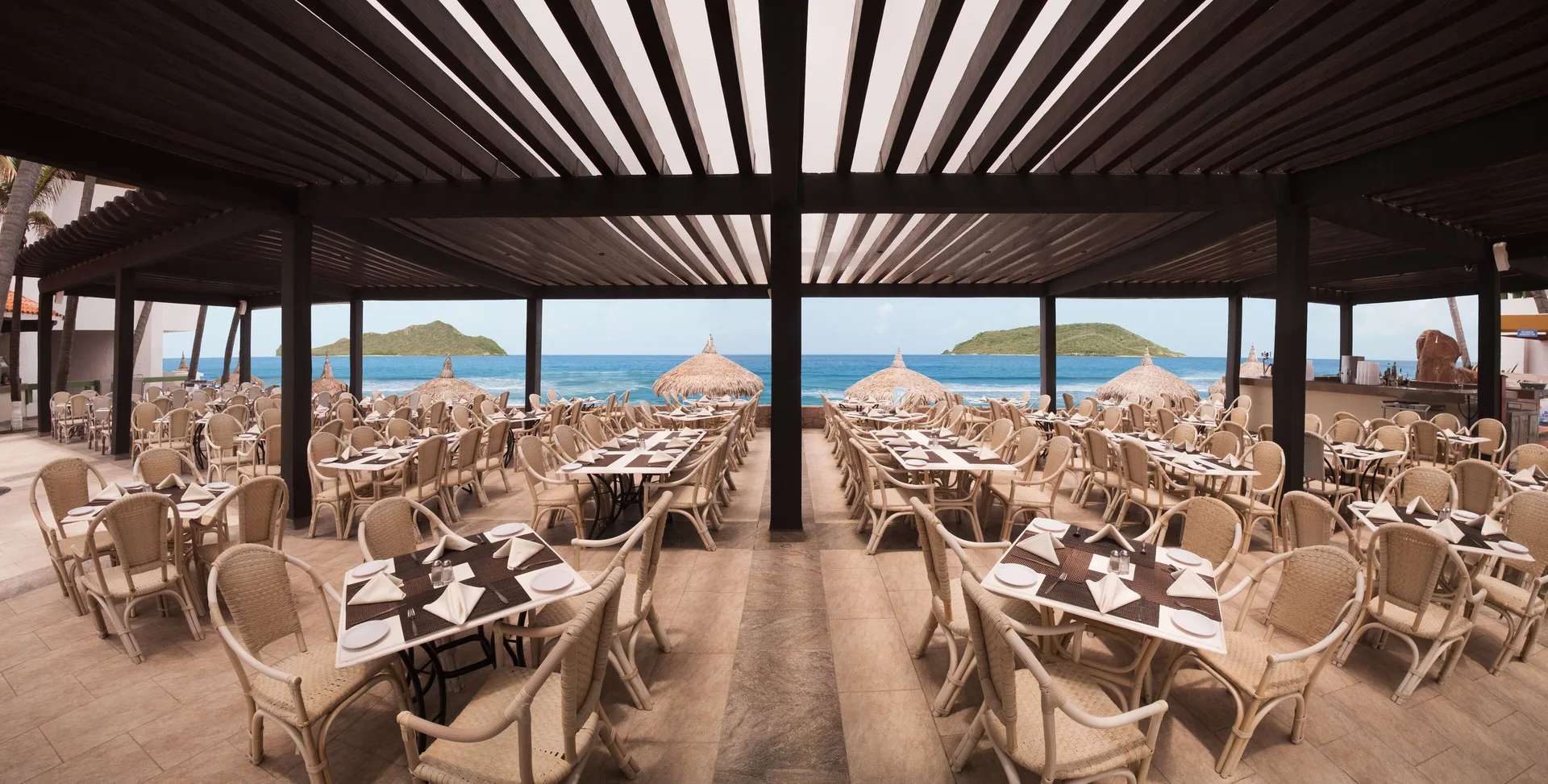 Oceanfront open-air dining terrace with set tables at El Cid Castilla Beach Hotel.