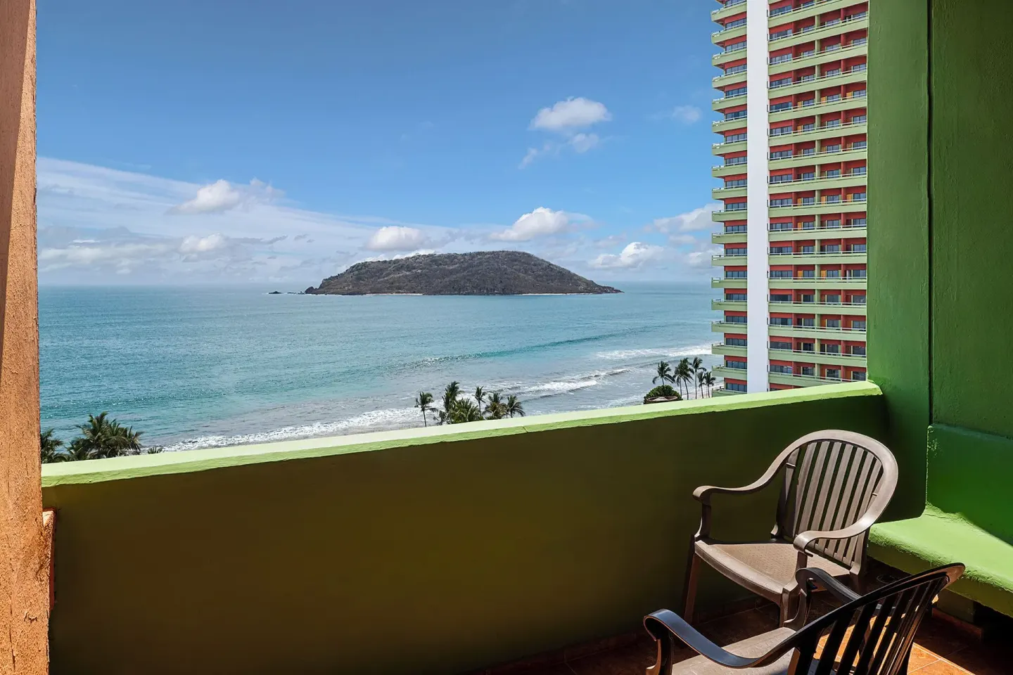 Balcony ocean view with chairs and island scenery at El Cid Castilla Beach Hotel.
