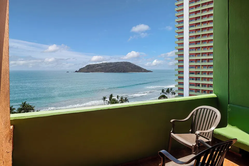 Balcony ocean view with chairs and island scenery at El Cid Castilla Beach Hotel.