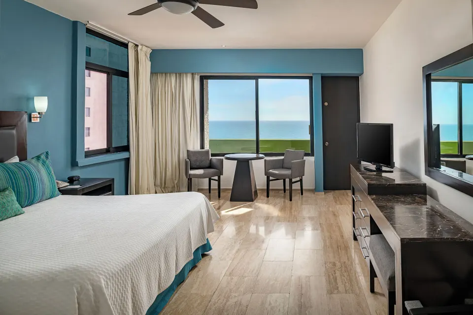 Standard Ocean View room with king bed, blue wall, and balcony view at El Cid Castilla Beach Hotel.