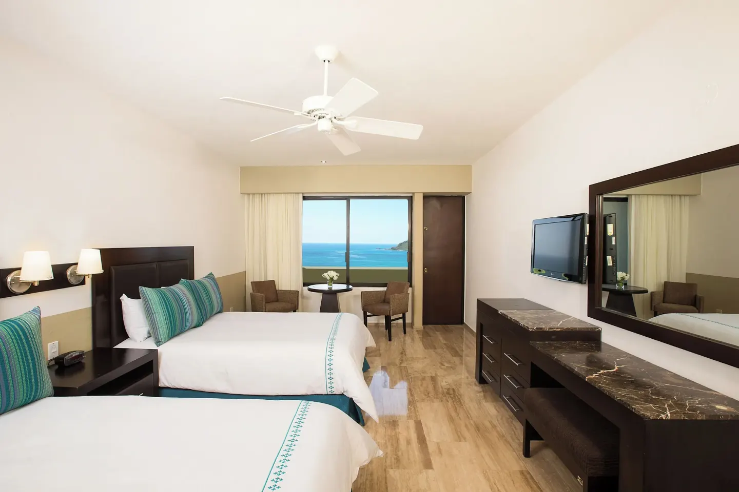 Standard Ocean View room with two beds, TV, mirror, and sea view at El Cid Castilla Beach Hotel.