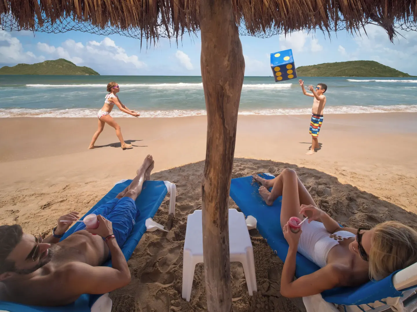 Beach loungers and children playing on the sand at El Cid El Moro Beach Hotel.
