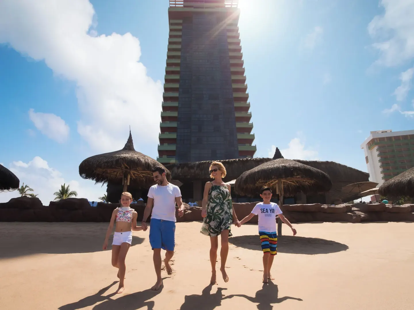 Family walking on the beach below the tower at El Cid El Moro Beach Hotel.