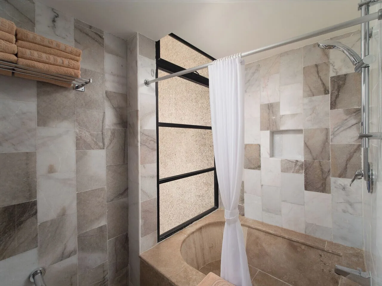 Tiled bathroom shower and round soaking tub at El Cid El Moro Beach Hotel.