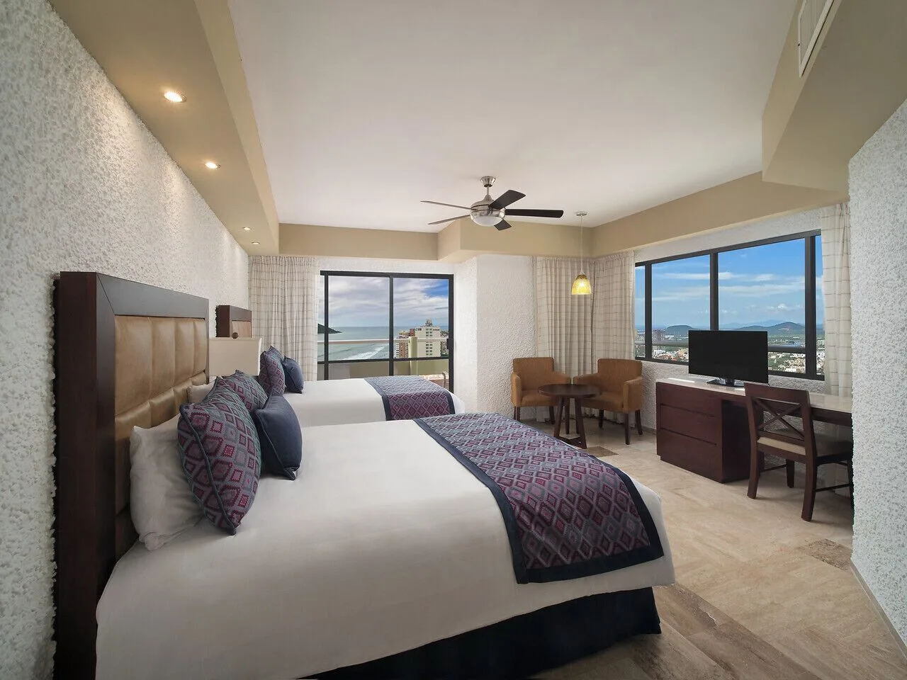 Two-bed guest room with ocean-facing windows at El Cid El Moro Beach Hotel.