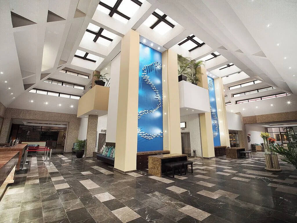 Spacious lobby with skylights and tall blue wall art at El Cid El Moro Beach Hotel.