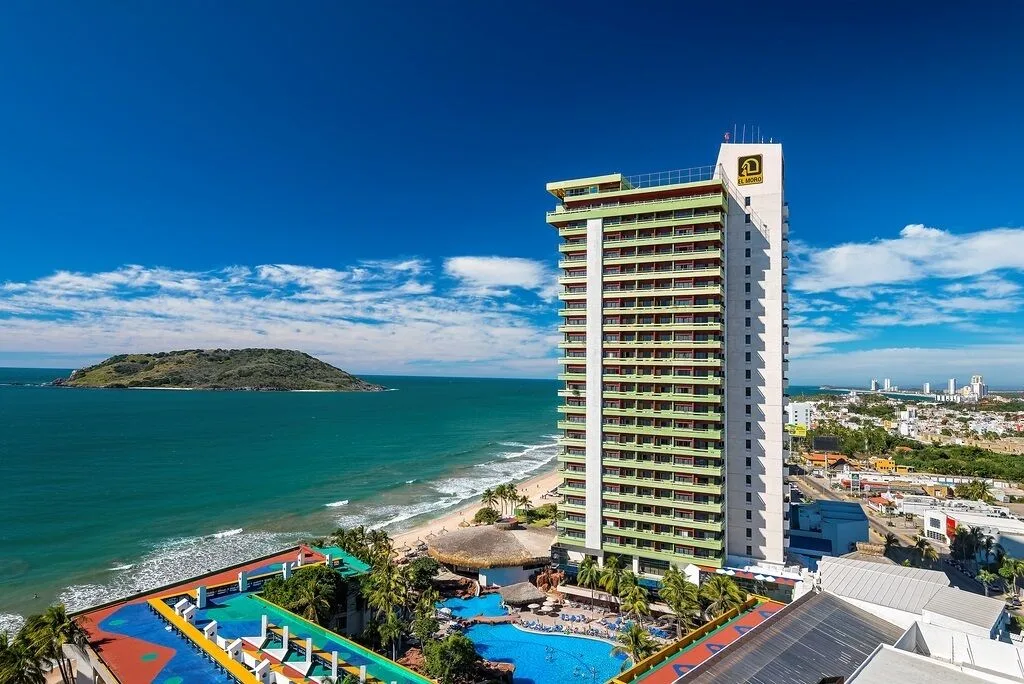 Oceanfront tower, pools, beach, and island view at El Cid El Moro Beach Hotel.