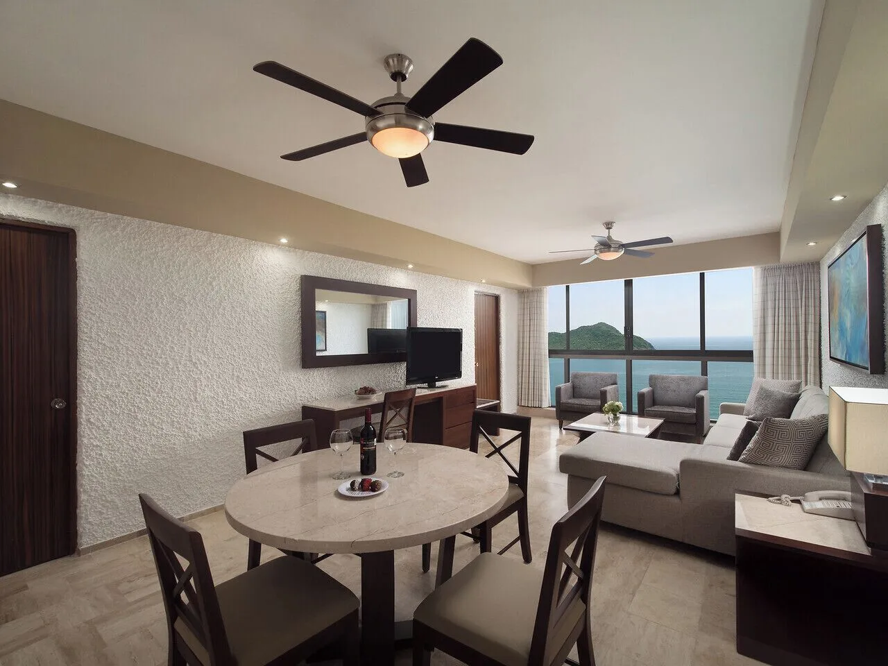 Suite living and dining area with ocean-facing windows at El Cid El Moro Beach Hotel.