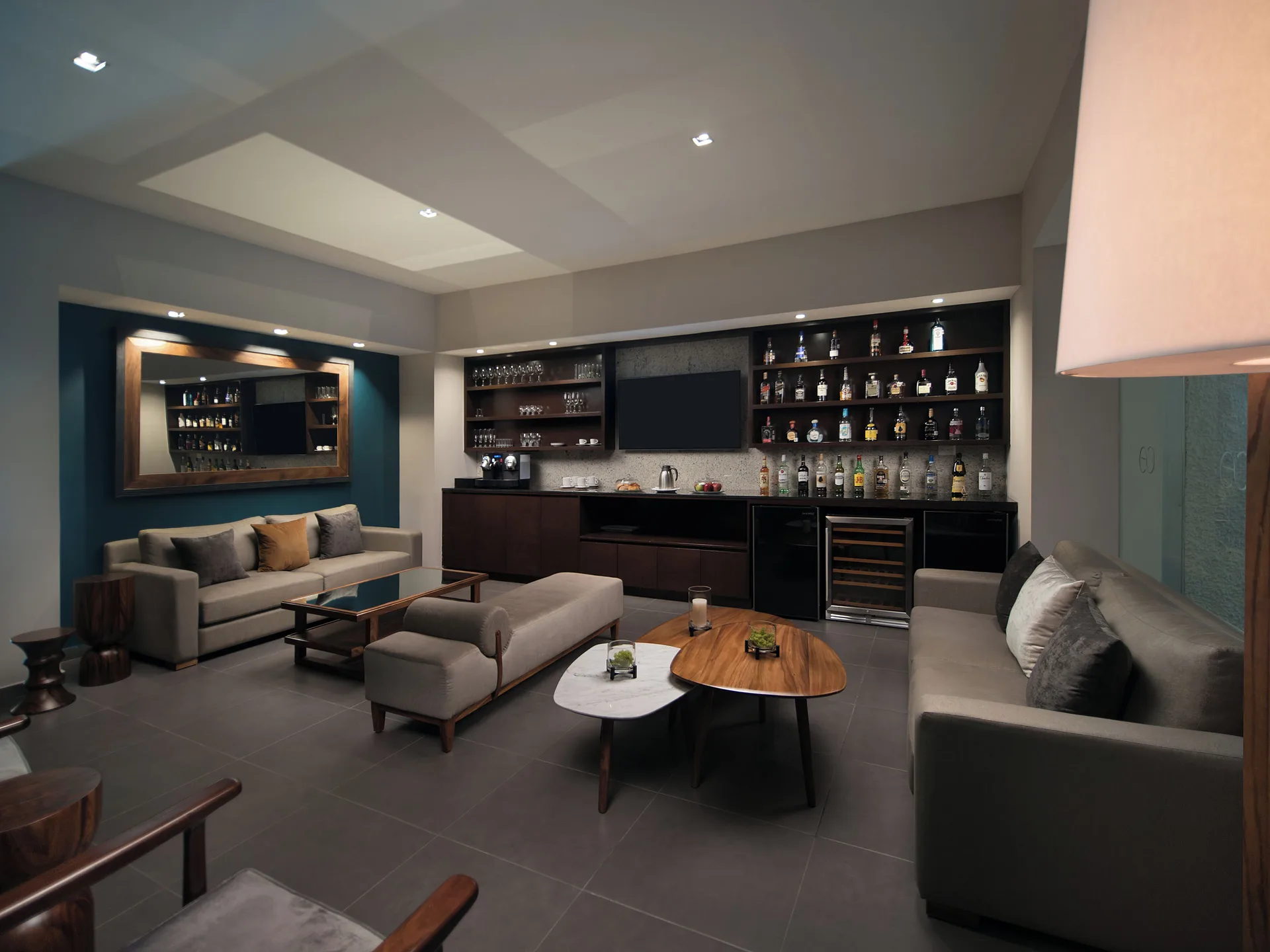 Lounge bar with sofas, tables, and backlit bottle shelves at El Cid El Moro Beach Hotel.