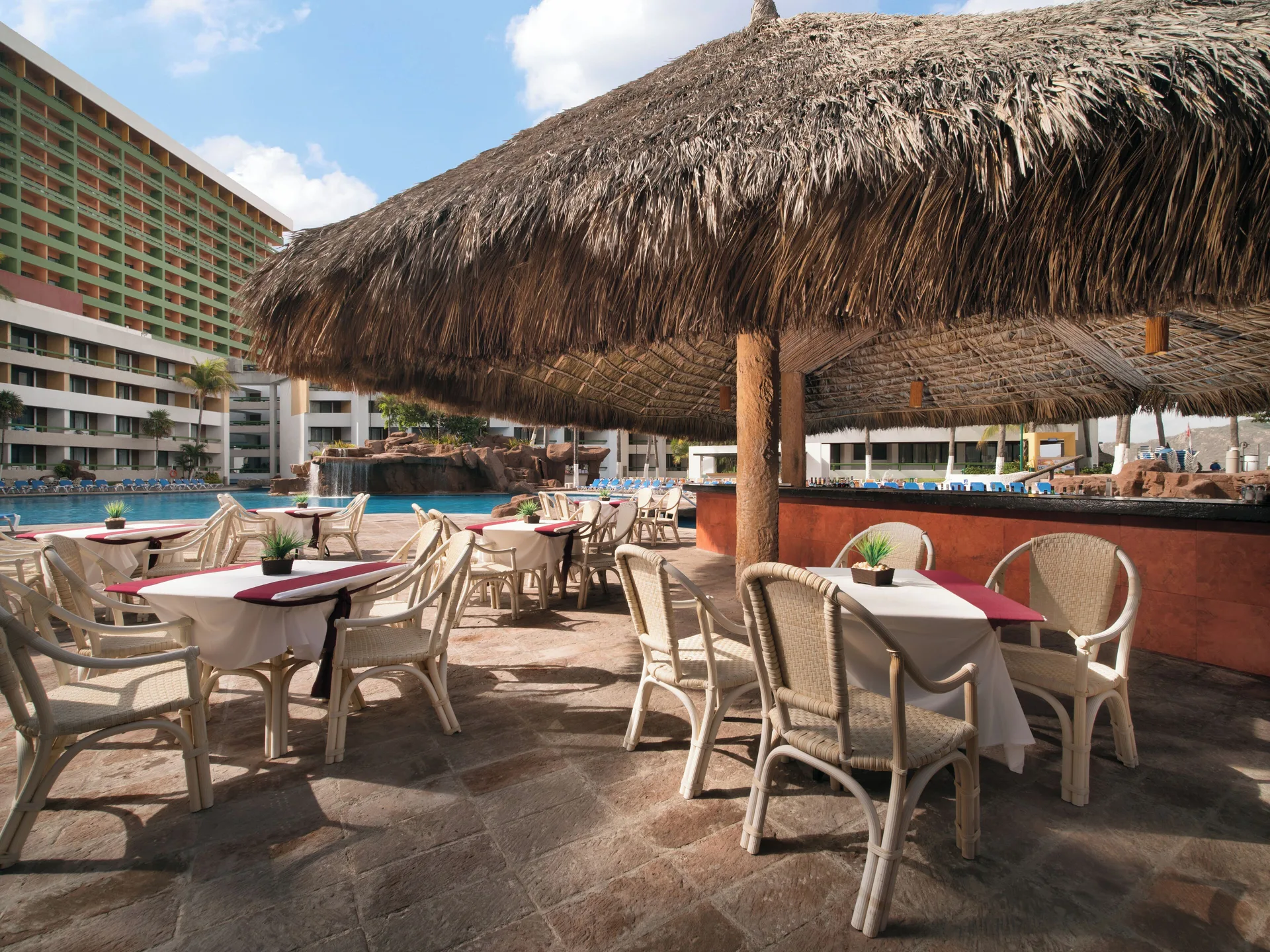 Poolside snack bar seating under a thatched roof at El Cid El Moro Beach Hotel.