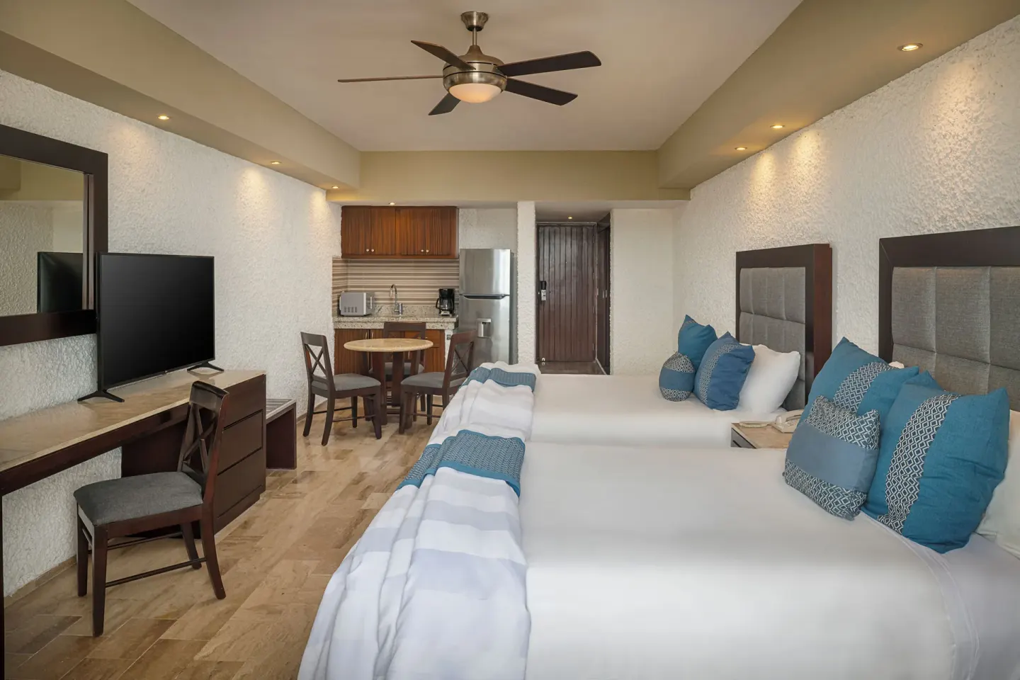 Two-bed room with kitchenette and TV console at El Cid El Moro Beach Hotel.
