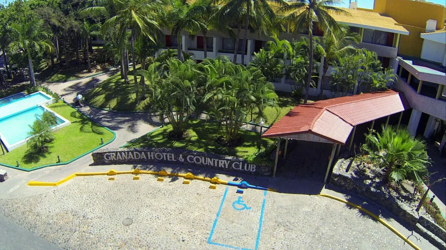 Aerial view of the entrance, palms and pool area at El Cid Granada Hotel.