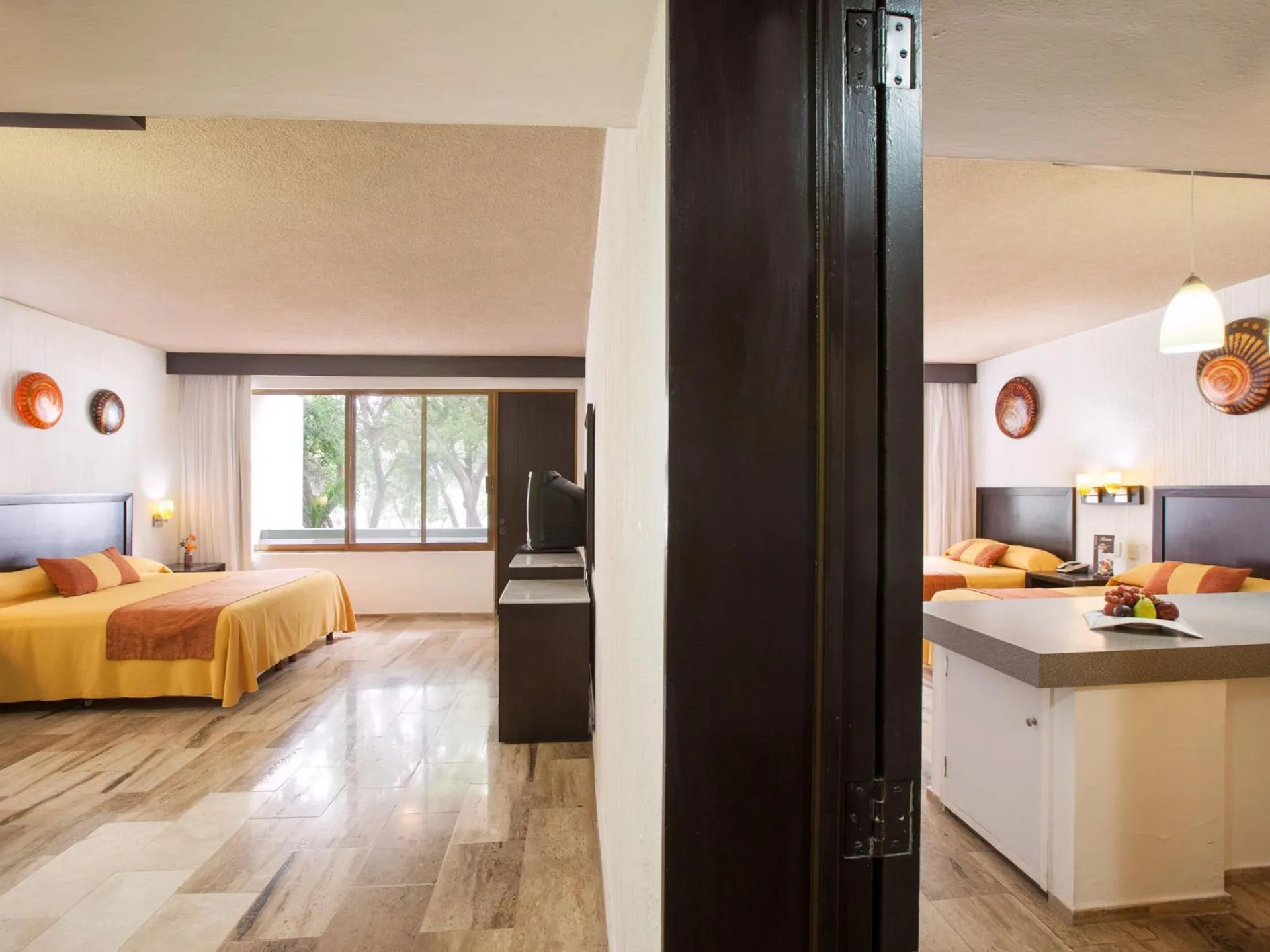 Connecting guest rooms with yellow bedding and kitchenette at El Cid Granada Hotel.