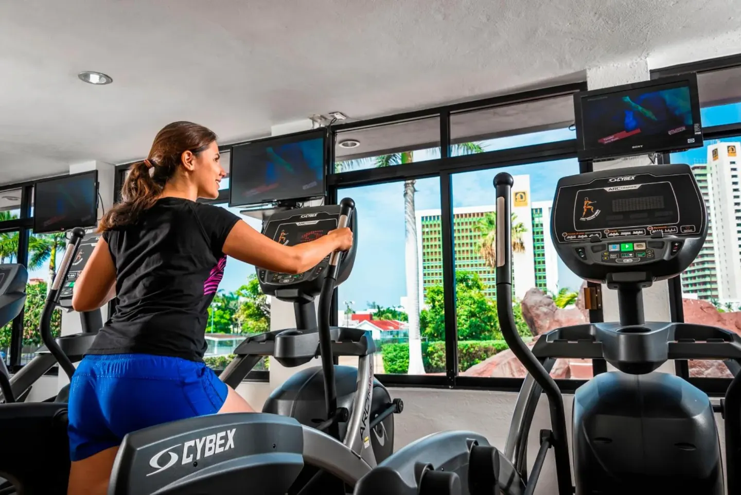 Guest using an elliptical machine in the fitness room at El Cid Granada Hotel.
