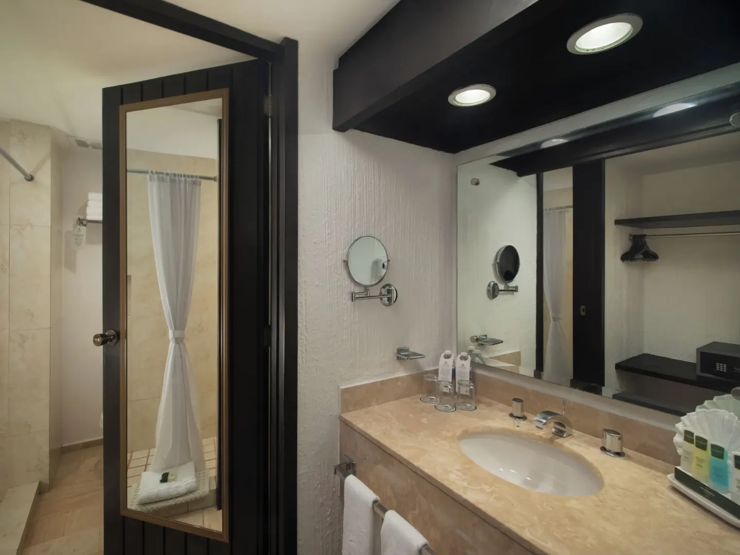 Guest bathroom sink, mirror, and walk-in shower at El Cid Granada Hotel.