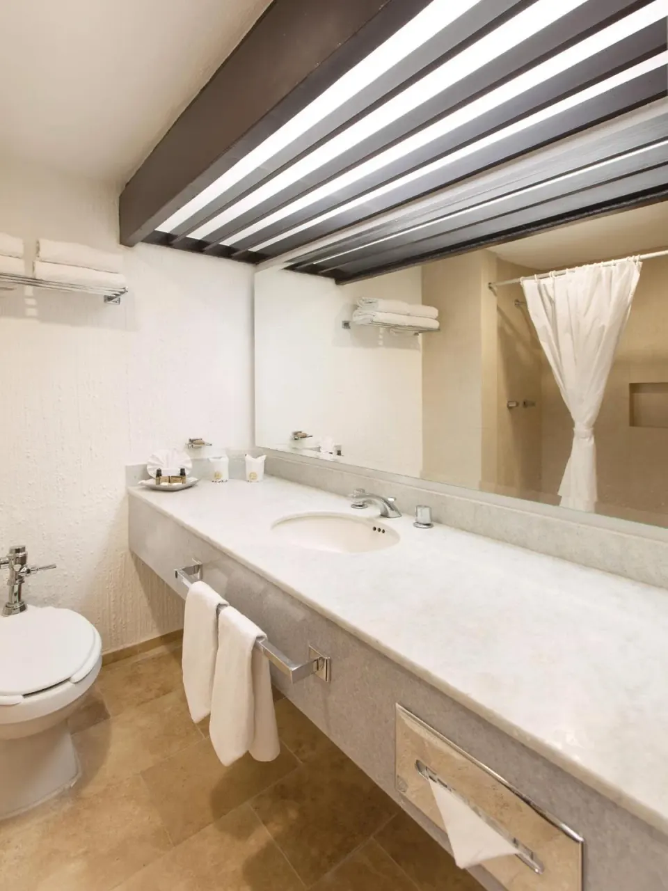 Guest bathroom with long vanity and shower curtain at El Cid Granada Hotel.